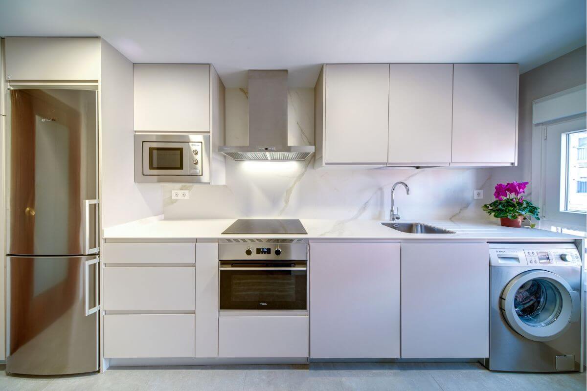 Cocina moderna reformada en Zaragoza con muebles blancos y encimera de diseño.